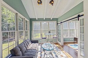 A sunroom with a sofa, a glass table, and large windows. - Bethany Lakes house with a community pool, gym, tennis & free WiFi (Bethany Beach)