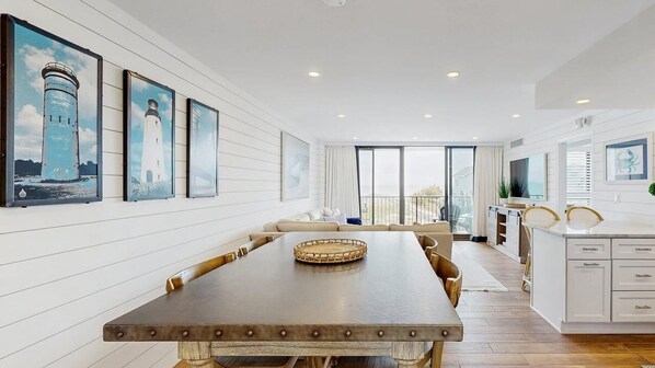 A modern dining area with a long table, cushioned seating, and artwork on the walls. - Sea Colony 2nd floor oceanside condo w/community pools, tennis, fitness center (Bethany Beach)