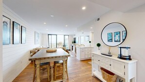 A modern kitchen with a central island, white cabinetry, and a large round mirror on the wall. - Sea Colony 2nd floor oceanside condo w/community pools, tennis, fitness center (Bethany Beach)