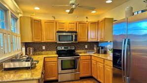 A kitchen with wooden cabinets, stainless steel appliances, a microwave, oven, and a refrigerator. - Bethany Bay house w/community pool, hot tub, tennis, on-site golf (Ocean View)