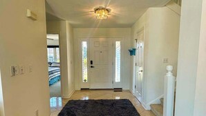 A hallway leading to a bedroom with a door, a dark rug, and a staircase. - Bethany Bay house w/community pool, hot tub, tennis, on-site golf (Ocean View)