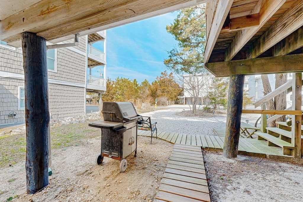 Ein überdachter Außenbereich mit Grill, Holzterrasse und Blick auf eine Wohngegend.