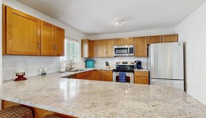 A kitchen with wooden cabinets, a stainless steel refrigerator, a microwave, and a stove. - Town of South Bethany house w/patio, grill, close to beach & restaurants (Bethany Beach)