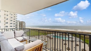 A balcony with a view of the beach, a pool, and a building in the background. - Sea Colony 5th floor condo with pools, tennis/pickle ball courts, fitness center (Bethany Beach)