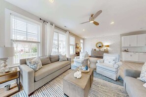 A spacious living room with a sofa, chairs, a coffee table, and a ceiling fan. - Town of Bethany Beach home near beach with firepit, bikes, fireplace, beach gear (Bethany Beach)