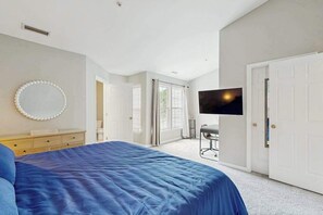 A bedroom with a bed, a TV, a mirror, and a door leading to another room. - South Hampton townhome with shared pool & tennis courts (Ocean View)