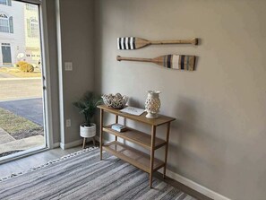 A wooden console table with decorative items, a patterned rug, and two wooden paddles on the wall. - South Hampton townhome with shared pool & tennis courts (Ocean View)