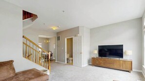 Una sala de estar con una escalera, un televisor y un mueble de madera.