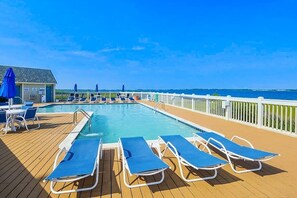 Un espace piscine avec des chaises longues et un bâtiment portant une enseigne.
