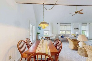 A dining area with a wooden table and chairs, a hanging light fixture, and a ceiling fan. - Charming Beach home with central ac, spacious Living Room and private deck (Bethany Beach)