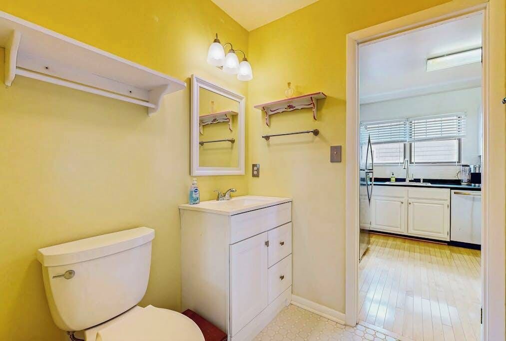 Baño con inodoro, lavabo, espejo y toallero.