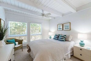 A bedroom with a bed, two bedside tables, a ceiling fan, and a window with a view of trees. - Ocean Village Beach block, pet friendly house w/patio, balcony, gas grill & WIFI (Bethany Beach)