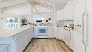 A kitchen with white cabinetry, a wooden floor, and a built-in oven. - Ocean Village Beach block, pet friendly house w/patio, balcony, gas grill & WIFI (Bethany Beach)