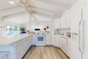 A kitchen with white cabinetry, a wooden floor, and a built-in oven. - Ocean Village Beach block, pet friendly house w/patio, balcony, gas grill & WIFI (Bethany Beach)