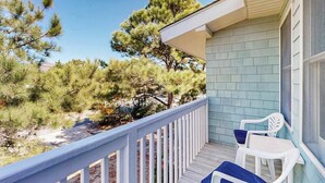 A balcony with a white railing, two white chairs, and a light blue building with a window. - Ocean Village Beach block, pet friendly house w/patio, balcony, gas grill & WIFI (Bethany Beach)