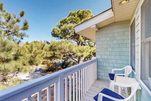 A balcony with a white railing, two white chairs, and a light blue building with a window. - Ocean Village Beach block, pet friendly house w/patio, balcony, gas grill & WIFI (Bethany Beach)