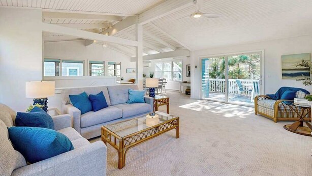 A spacious living room with a high ceiling, large windows, and a balcony with outdoor furniture. - Ocean Village Beach block, pet friendly house w/patio, balcony, gas grill & WIFI (Bethany Beach)
