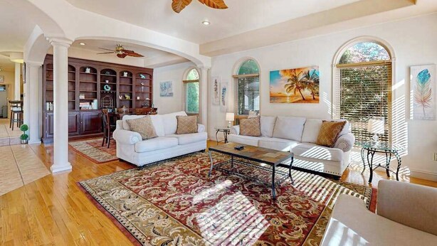 A spacious living room with a large ceiling fan, a fireplace, and a view of the outdoors through large windows. - Town of Ocean View pet friendly house with a private pool! (Bethany Beach)