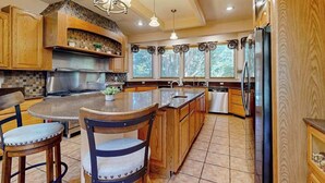 A kitchen with wooden cabinets, a central island, a stove, and a refrigerator. - Town of Ocean View pet friendly house with a private pool! (Bethany Beach)