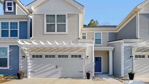 A multi-story residential building with a garage, a covered entryway, and a blue door.