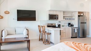 Een moderne keuken met een centraal eiland, een zithoek met een bank en stoelen, en een aan de muur bevestigde televisie.