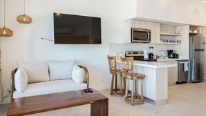 Een moderne keuken met een flatscreen televisie, een bank en een houten salontafel.