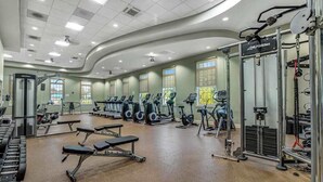 Une salle de sport équipée de machines de cardio, de bancs de musculation et d’un support à squats.
