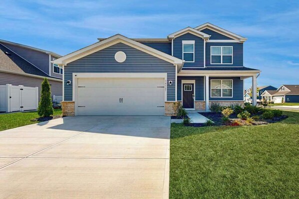 Ein zweistöckiges Haus mit Garage, einer Rasenfläche und einem kleinen Garten.