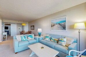 A living room with a sofa set, a coffee table, a lamp, and a painting on the wall. - Sea Colony Ocean 1st floor condo w/ elevator, tennis court, and basketball court (Bethany Beach)