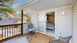 Ein überdachter Balkon mit einer Schiebetür, die zu einem Schlafzimmer mit Bett und Stuhl führt.