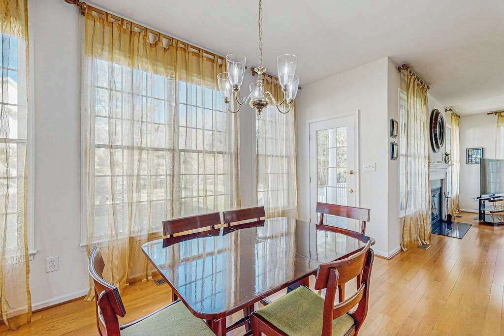A dining area with a glass table, wooden chairs, and a chandelier.