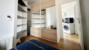 Een slaapkamer met een bed, een kledingkast en een wasmachine op de achtergrond.