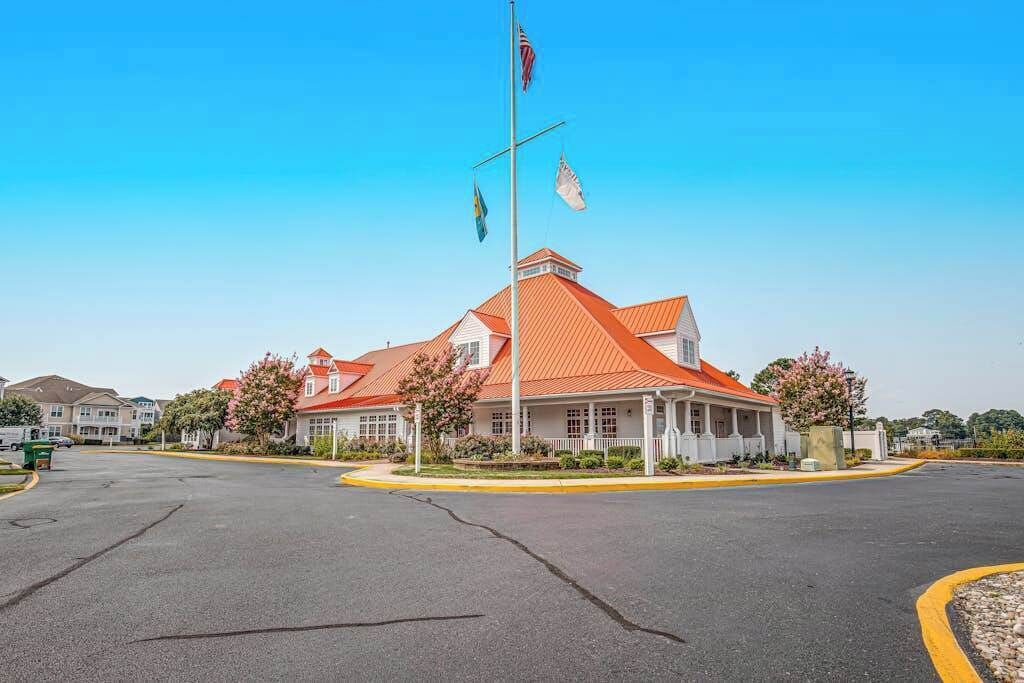 A building with a red roof, a flagpole with flags, and a clear sky.