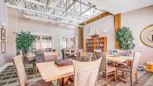 A spacious room with a high ceiling, large windows, and a wooden bookshelf. - Luxury Bayside at Bethany Lakes Townhome with AC, shared pool & tennis court (Ocean View)