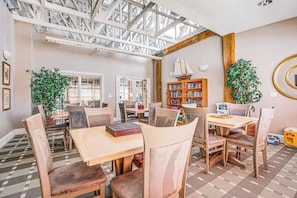 Ein geräumiges Zimmer mit hohen Decken, großen Fenstern und einem Bücherregal aus Holz.