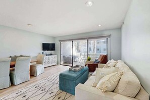 Een moderne woonkamer met een bank, een poef en een flatscreen televisie.