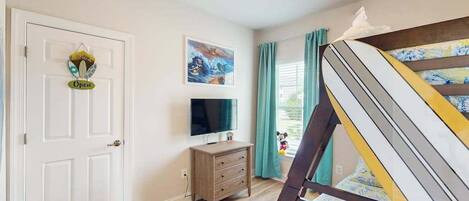 Una habitación con cama, televisión, cómoda y una puerta con un letrero.