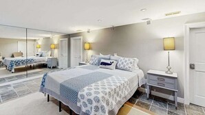 A bedroom with a large bed, bedside tables, a mirror, and a door. - Town of Rehoboth Beach - 38242 Robinson Dr. Unit #1 (Rehoboth Beach)