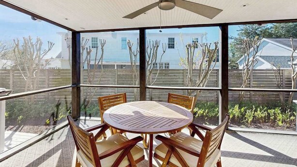 A covered outdoor dining area with a round table and chairs, large windows, and a ceiling fan. - Town of Rehoboth Beach - 38242 Robinson Dr. Unit #1 (Rehoboth Beach)