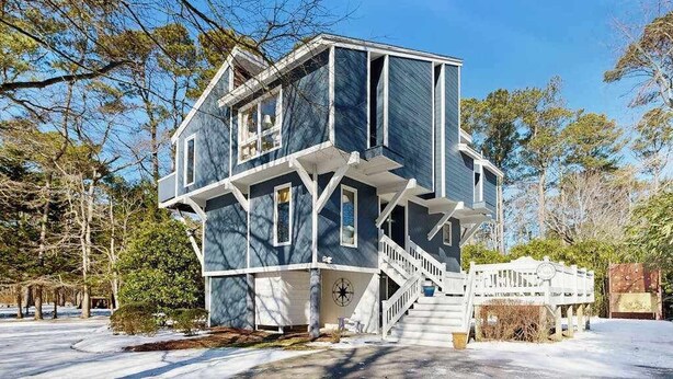 Ein zweistöckiges Haus mit Balkon, Treppe und Veranda.