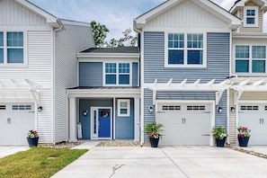 A row of two-story houses with attached garages, a front porch, and potted plants. - Friendship Creek - 35058 Dundee St | Charming townhouse with pool & patio (Frankford)