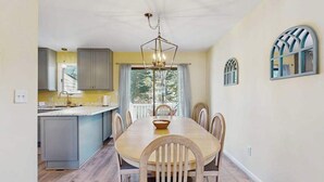 A dining area with a wooden table and chairs, a chandelier, and a view of the outdoors. - Bethany Pines townhouse w/community pool & tennis, close to beach (Bethany Beach)