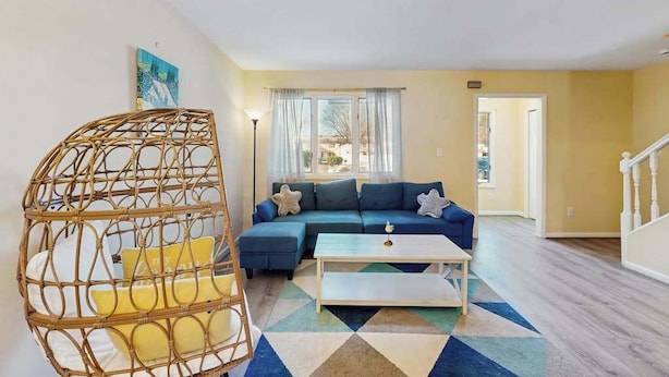 A living room with a sofa, a coffee table, a hanging chair, and a view through a window. - Bethany Pines townhouse w/community pool & tennis, close to beach (Bethany Beach)