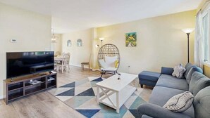 A living room with a TV, sofa, coffee table, and a chair. - Bethany Pines townhouse w/community pool & tennis, close to beach (Bethany Beach)