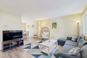 Ein Wohnzimmer mit Fernseher, Sofa, Couchtisch und Sessel.