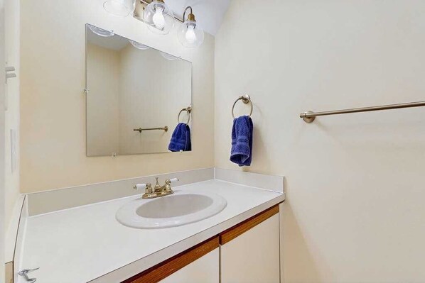 A bathroom with a white sink, a mirror, and two towels hanging on towel bars. - Bethany Pines townhouse w/community pool & tennis, close to beach (Bethany Beach)