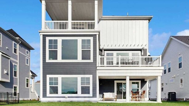 Un edificio residenziale a due piani con un balcone, ampie finestre e un portico coperto.