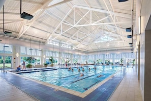 Une piscine intérieure dotée d’un haut plafond et de grandes fenêtres.