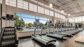 Een sportschool met loopbanden, een stair climber en grote ramen.