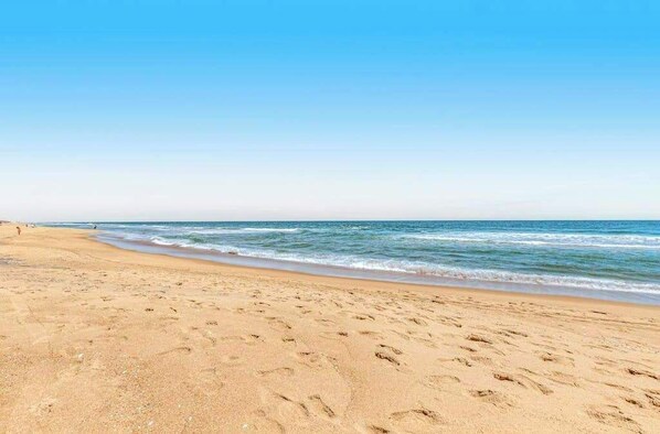 A beach with footprints in the sand and a clear blue sky. - Oceanfront complex with beach access & charm - pools, tennis, fitness centers (Bethany Beach)